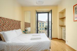 a bedroom with a white bed and a large window at Brera - San Marco Cozy Apartment in Milan
