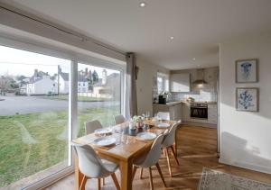 a dining room with a table and a large window at Ty Golau in Llanbedrog