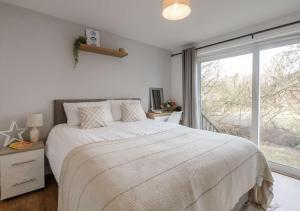 a bedroom with a large bed and a large window at Ty Golau in Llanbedrog