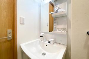 een badkamer met een witte wastafel en een spiegel bij TASUKI smart Higashinakano in Tokyo