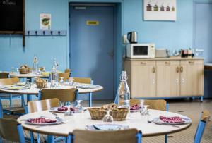 a dining room with tables and chairs and a kitchen at Hostellerie des Grands Chapeaux in Bayeux