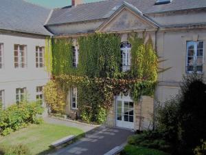 um edifício coberto de heras com uma casa branca em Hostellerie des Grands Chapeaux em Bayeux