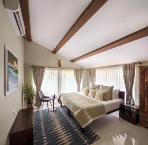 a bedroom with a large bed and a chair at amã Stays & Sluice House Lonavala in Lonavala