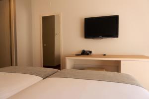 a hotel room with a bed and a desk with a television at Hotel Vértice Chipiona Mar in Chipiona