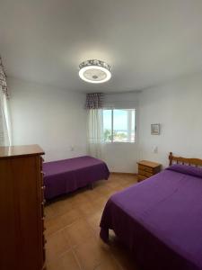 a bedroom with two purple beds and a window at Alpen1 Finca Simo in Peniscola