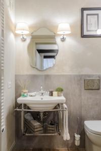 ein Bad mit einem Waschbecken und einem Spiegel in der Unterkunft Paolo Guinigi, Elegant Apartment Suite, Masterful Interior inside the Walls of Lucca in Lucca