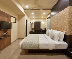 a hotel room with a bed and a television at Hotel Atria, Kolhapur- Opposite To Central Bus Station in Kolhapur