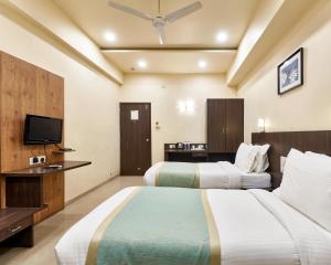 ein Hotelzimmer mit 2 Betten und einem Flachbild-TV in der Unterkunft Hotel Atria, Kolhapur- Opposite To Central Bus Station in Kolhapur