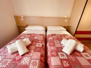 1 dormitorio con 2 camas y mantas rojas y blancas en CONDOMINIO SATURNO, en Lido di Jesolo