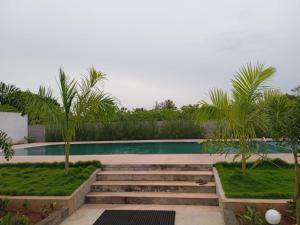 a swimming pool with stairs and palm trees at Paradise Forest Resort in Pondicherry