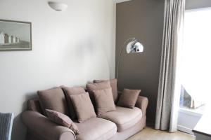 a couch sitting in a living room with a window at Fleur de Ré in Loix