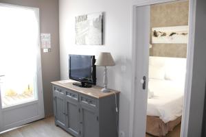 a bedroom with a tv on a dresser with a bed at Fleur de Ré in Loix
