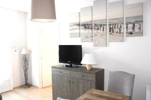 a living room with a tv on a dresser with a television at Fleur de Ré in Loix