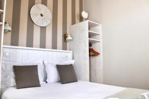 a bedroom with a white bed and a striped wall at Fleur de Ré in Loix