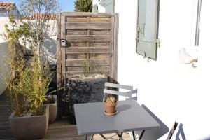 a table and chair on a patio with potted plants at Fleur de Ré in Loix