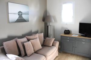 a living room with a couch and a television at Fleur de Ré in Loix