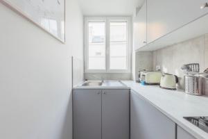 une cuisine blanche avec un évier et une fenêtre dans l'établissement Lovely and cosy apartment 4P1BR, à Paris