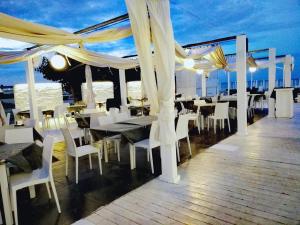 un restaurante con mesas blancas y sillas en una terraza en Hotel Ristorante Il Gambero, en Porto SantʼElpidio