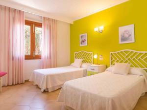 two beds in a hotel room with yellow walls at Bugambilla in Playa de Muro