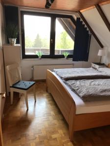 een slaapkamer met een bed, een stoel en een raam bij Ferienwohnung Weitblick am Kurpark in Braunlage