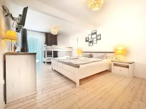 a white bedroom with a large bed and a television at WAGNERS Hotel im Frankenwald in Steinwiesen