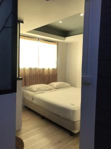 a bedroom with a white bed and a window at Rod Fai Fah Apartment in Bangkok
