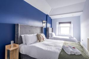 a bedroom with two beds and a blue wall at Newly Renovated Cotham House #2 by Prescott Apartments in Bristol