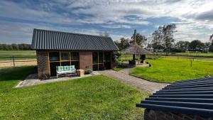 una pequeña casa con un banco y un campo de hierba en Gastenverblijf De Handwijzer, en Hengelo