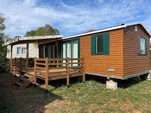 Cabaña de madera con porche y casa en Camping La Prairie, en Le Muy