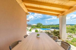 a wooden table on a patio with a view of a pool at Villa Emini by IstriaLux in Novaki Motovunski