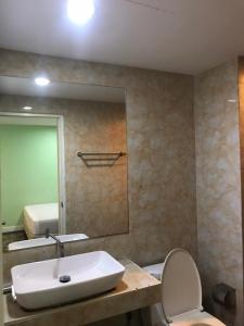 a bathroom with a sink and a toilet and a mirror at Rod Fai Fah Apartment in Bangkok