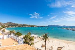 Elle offre une vue sur une plage bordée de palmiers et de bateaux. dans l'établissement Apartamento Brisas, à Port de Pollença