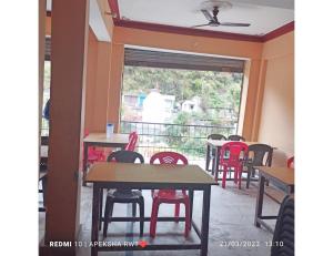 un restaurante con mesas y sillas y una gran ventana en Shri Garud Ganga, Pipalkoti en Chamoli