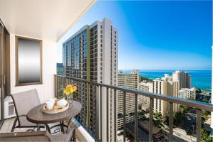 a balcony with a table and chairs and a view of the city at Ocean view high-floor condo with lanai & beach access in Honolulu