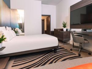 ミラノにあるノボテル ミラノ リナート エアロポルト ホテルのベッドとデスクが備わるホテルルームです。