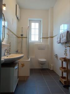 a bathroom with a sink and a toilet and a window at Ferienwohnung Gasthof Port - a84059 in Naunheim