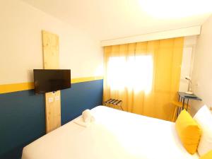 a room with a bed and a window and a television at greet hotel Grenoble Centre Gare in Grenoble