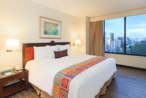 キトにあるLa Quinta by Wyndham Quitoの大きなベッドと大きな窓が備わるホテルルームです。