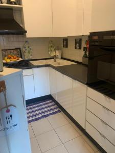 una cocina con armarios blancos y electrodomésticos negros en La casa di Miretta, en Chieti