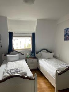 two twin beds in a bedroom with a window at Linde Restaurant & Hotel in Trossingen