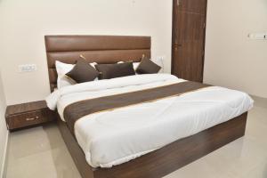 een groot bed met een houten hoofdeinde in een slaapkamer bij APEX HOTEL in Amritsar