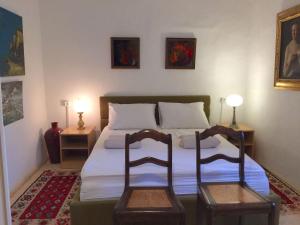 ein Schlafzimmer mit einem Bett mit zwei Stühlen in der Unterkunft Brač, Supetar, ART HOUSE, Dreamy Dalmatian vacation home, 80m from sea in Supetar