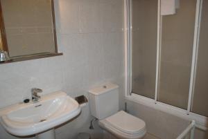 a white bathroom with a toilet and a sink at Hostal Gran Sol in Llança