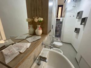 een badkamer met een wastafel, een spiegel en een toilet bij Rose Rosse - Sicily Holiday House in Racalmuto