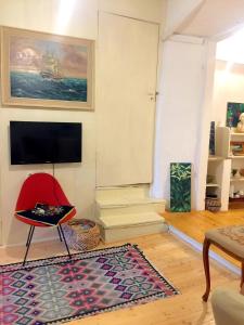 ein Wohnzimmer mit einem roten Stuhl und einem Teppich in der Unterkunft Brač, Supetar, ART HOUSE, Dreamy Dalmatian vacation home, 80m from sea in Supetar