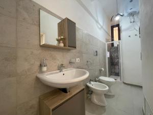 bagno con lavandino, servizi igienici e specchio di Rose Rosse - Sicily Holiday House a Racalmuto