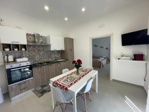 a kitchen with a table with a vase of flowers on it at Rose Rosse - Sicily Holiday House in Racalmuto
