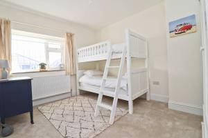 a bedroom with a white bunk bed and a window at WALK TO THE BEACH, spacious cottage with sea views in Saint Merryn