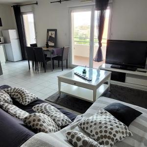 sala de estar con sofá y mesa con almohadas en Spacieux appartement résidence calme en Fonsorbes