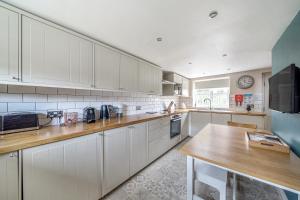 a kitchen with white cabinets and a wooden counter top at Host & Stay - Great Habton Cottage in Malton